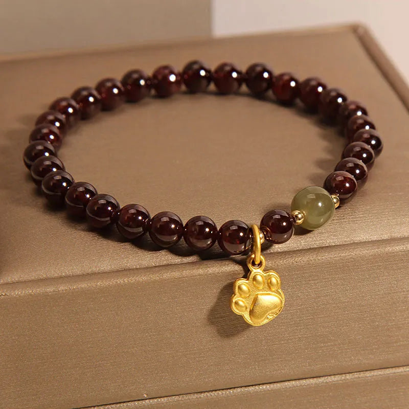 Women's adjustable crystal bracelet with a cat's paw shaped garnet stone centrepiece.