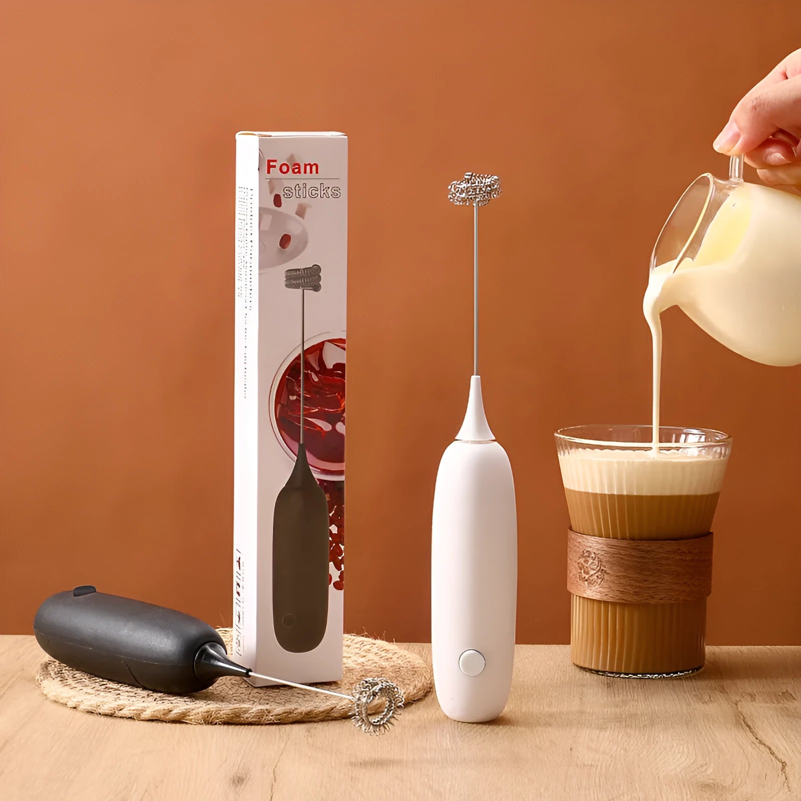 Black and white electric hand-held milk frother for coffee preparation on kitchen counter