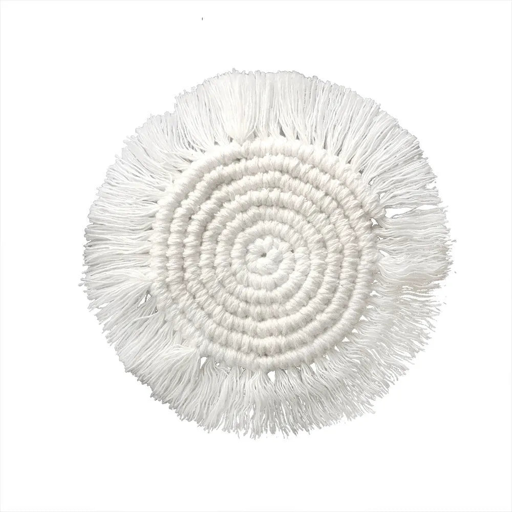 Hand-woven round beige cotton string coaster on a wooden table with a glass of water