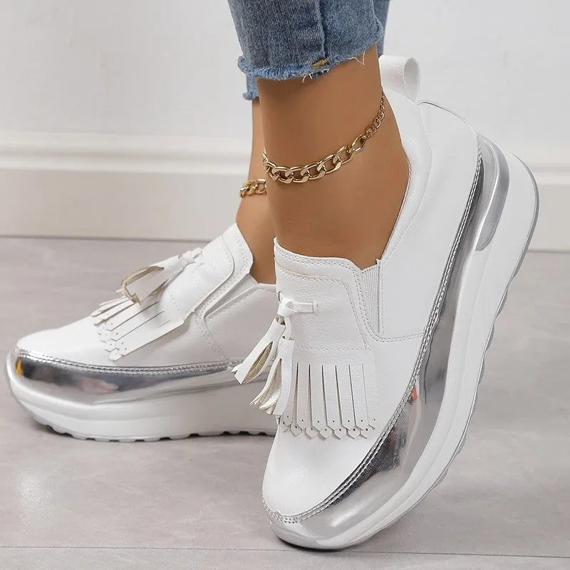 Women's black casual platform shoes with tassel detail and a low wedge heel on a white background.