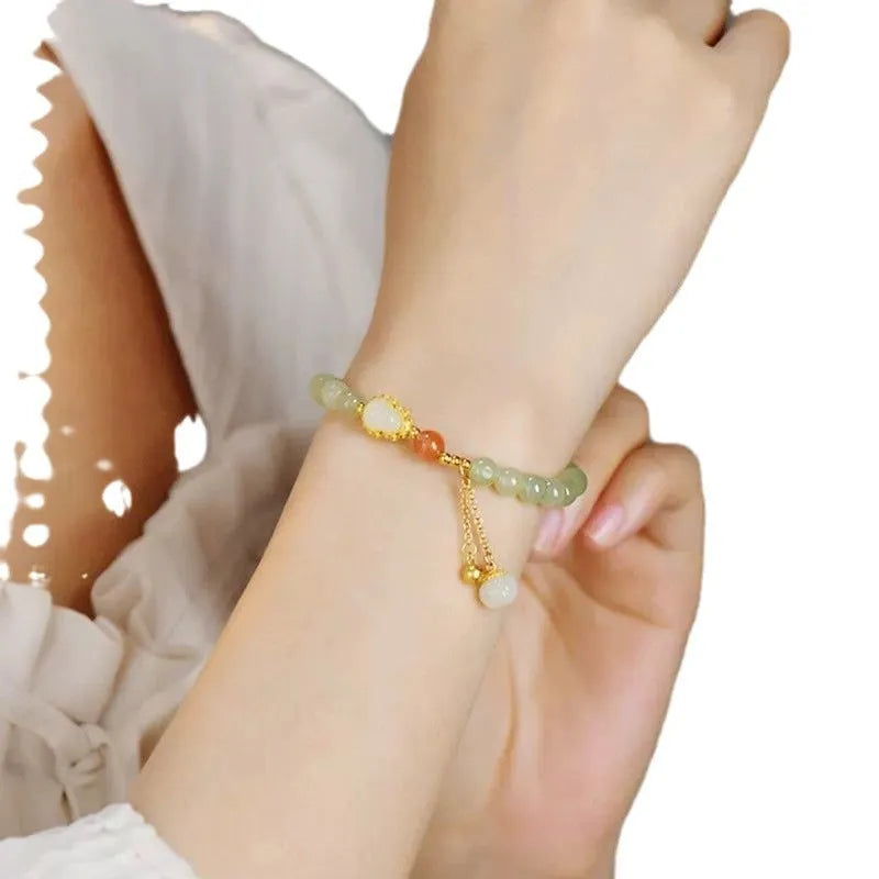 Jade women's bracelet with gold-plated fu character and a central gourd charm on wrist.