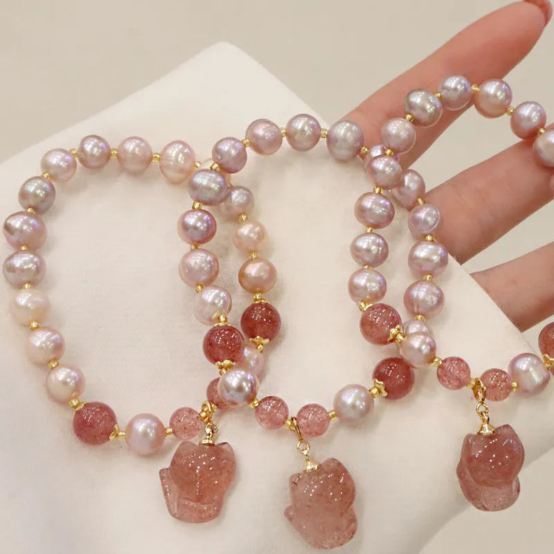 Women's light pink freshwater pearl bracelet with strawberry quartz and fox charm detailing
