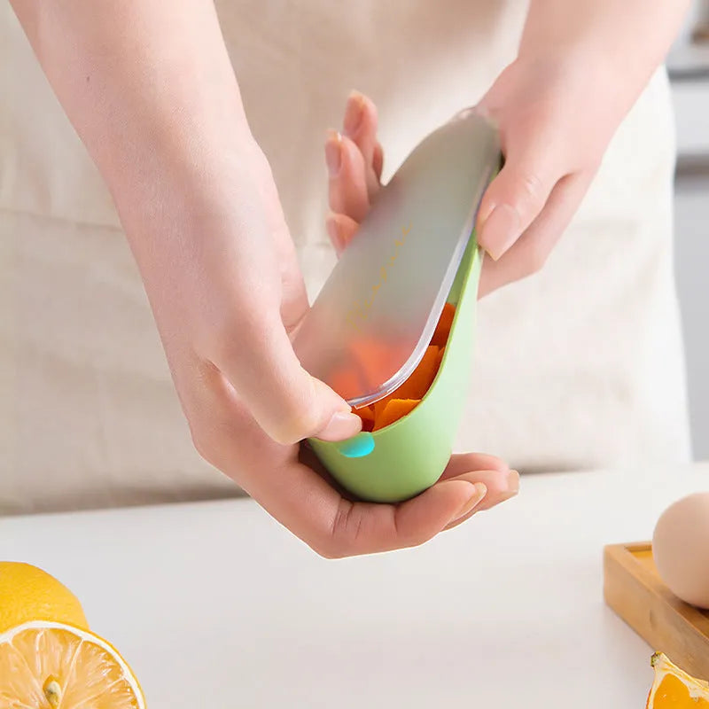 Dark green kitchen peeler with a storage tube, stainless steel blade, and non-slip plastic handle on a worktop.