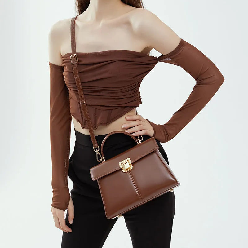 Women's black leather shoulder bag with vachette clasp showing interior zippered compartments