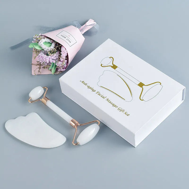 White jade double-headed facial roller and gua sha scraping tools on wooden storage board