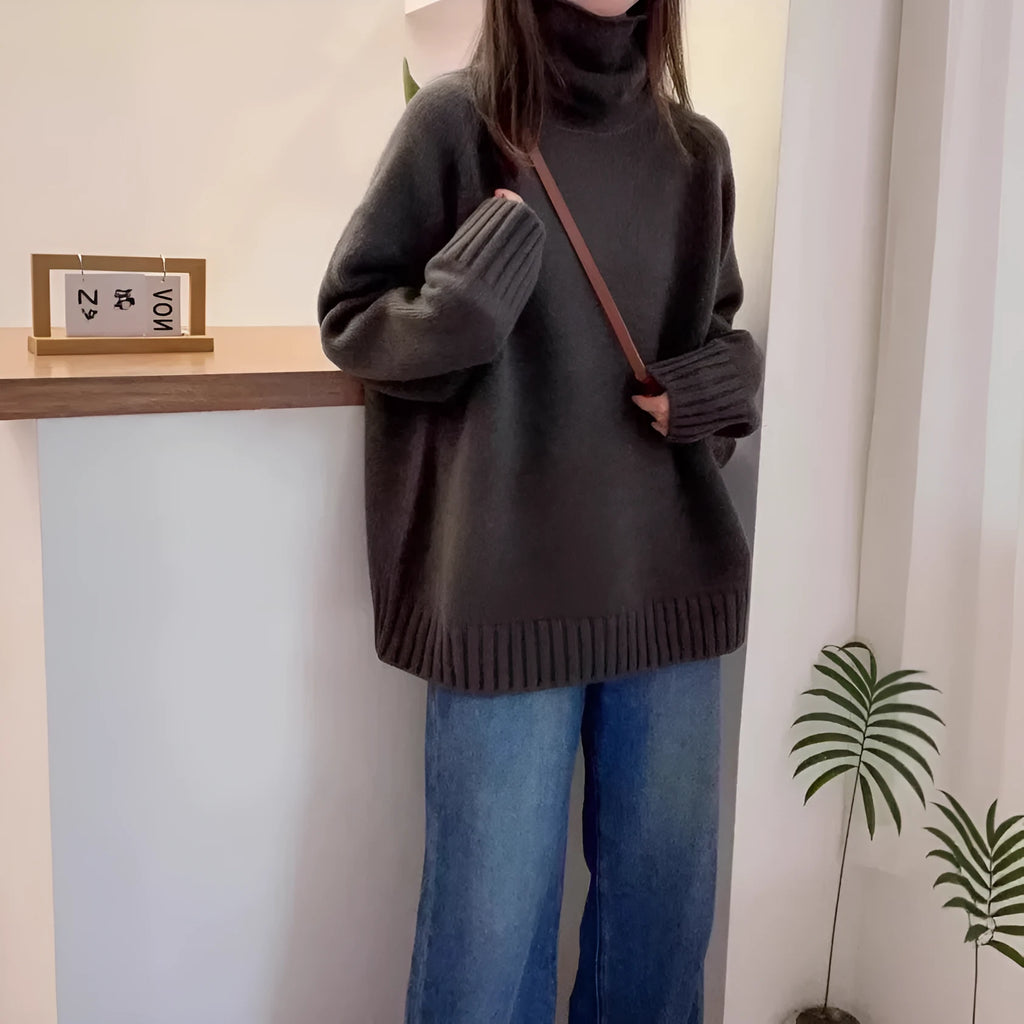 Women's loose grey turtleneck sweater with a thick 3D patterned texture and curling collar.