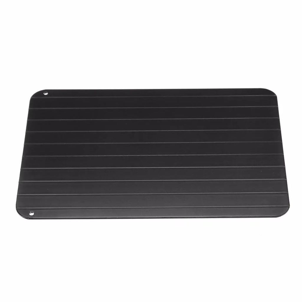 Black aluminium quick defrosting tray for thawing meat and frozen food on a kitchen counter.