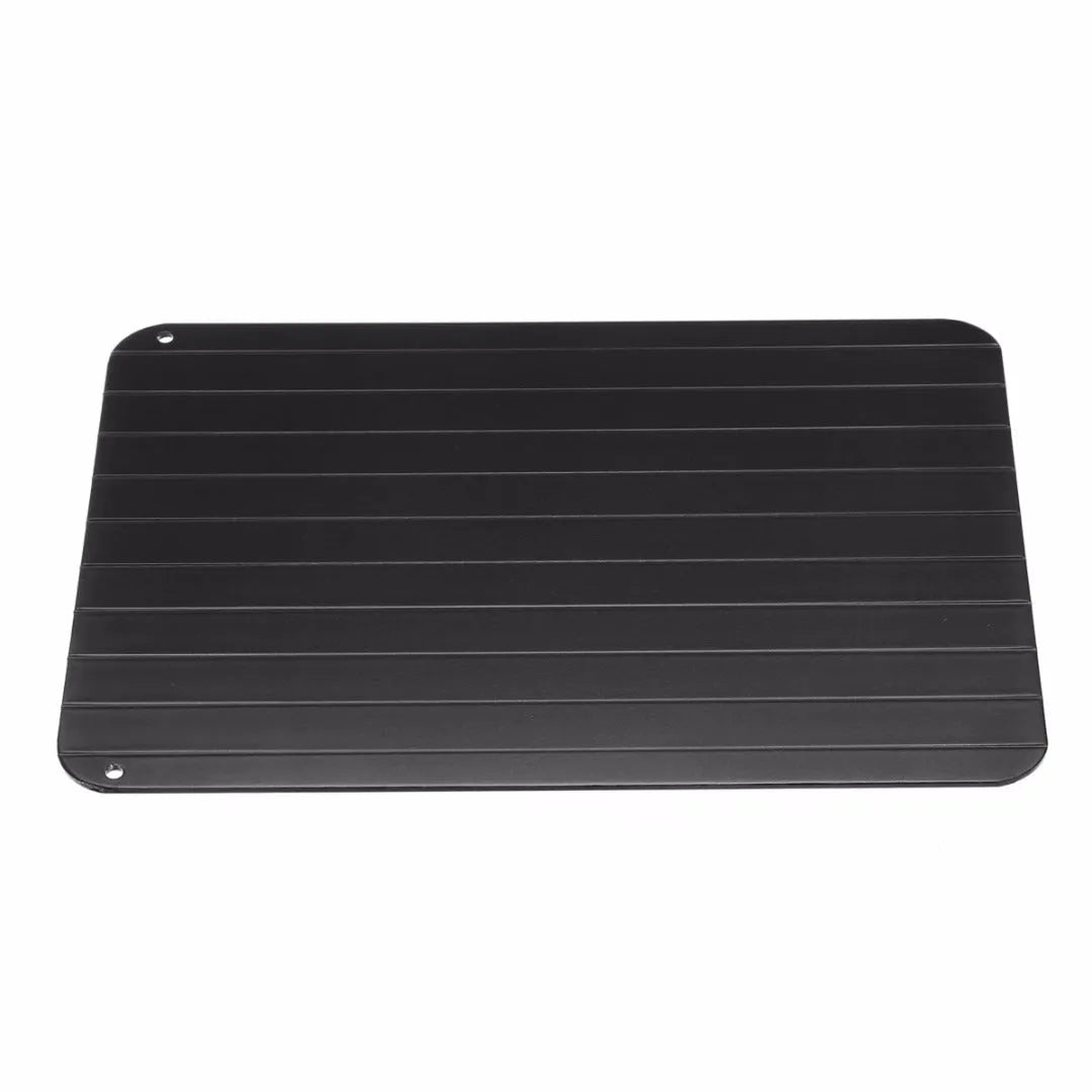 Black aluminium quick defrosting tray for thawing meat and frozen food on a kitchen counter.