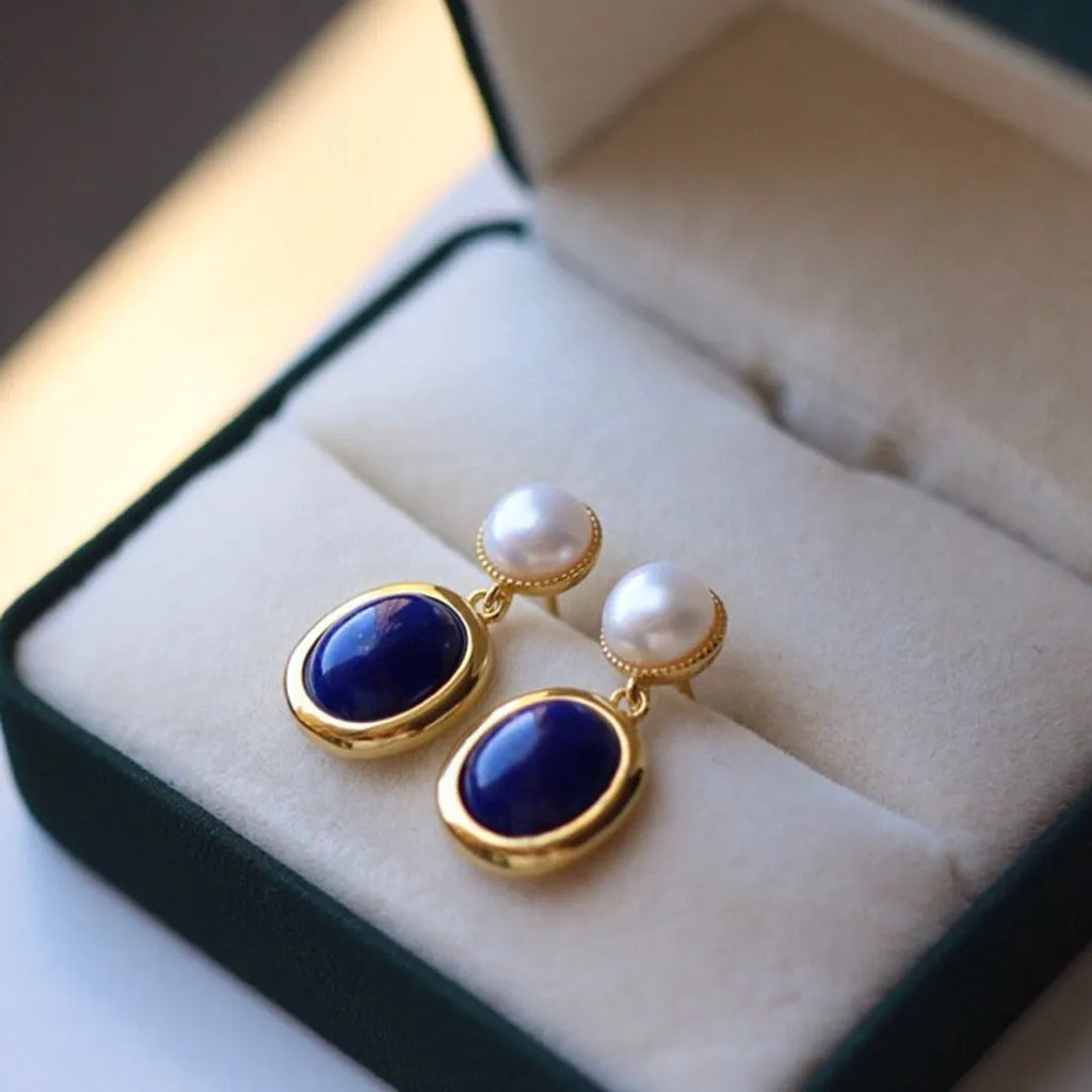 A pair of simple silver earrings with blue lapis lazuli pearls and auspicious pattern details.