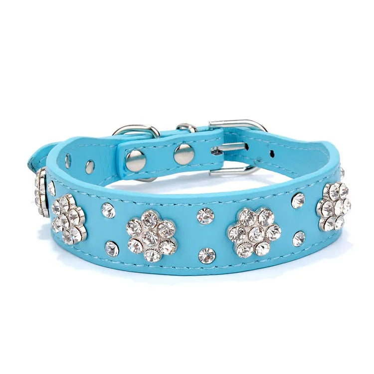 Close-up of a black PU leather dog collar with sparkling rhinestone flower studs and a metal D-ring