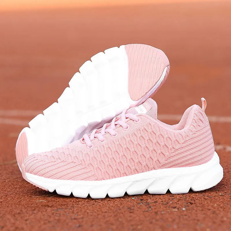 Women's black and pink running shoes showing fly weave upper texture and rubber outsole.