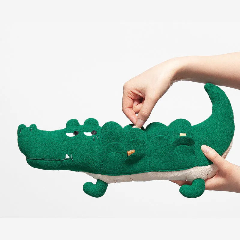 Green soft plush toy dog with floppy ears and embroidered face, lying on a white background.