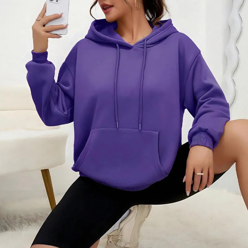 Women's loose grey sweatshirt with a front pocket and drawstring waist, worn with jeans.