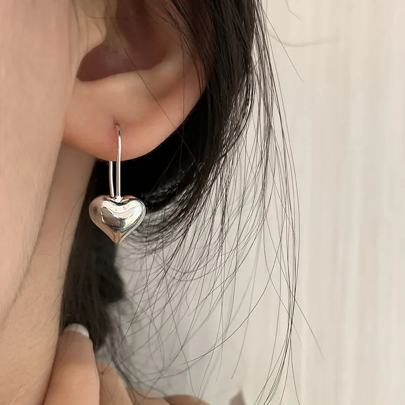 Silver-coloured three-dimensional heart-shaped earrings with glossy finish on copper