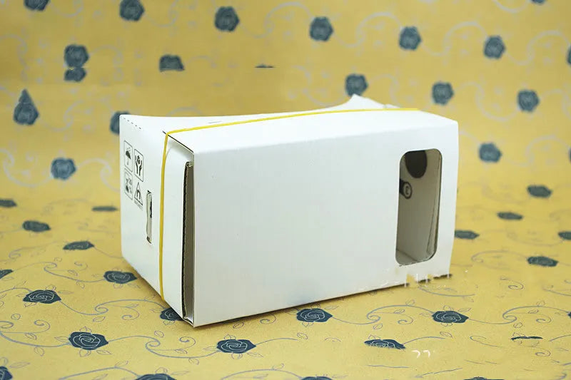 Pink and white cardboard VR glasses for smartphones with 3D lenses and a rubber strap.