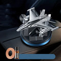 Silver solar powered rotating fighter jet perfume ornament on a car dashboard.