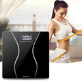 Black electronic digital body scale on a floor with a 180kg maximum capacity.