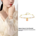 Close-up of a women's pink cherry blossom pendant and Hetian jade bead bracelet made from S925 silver.
