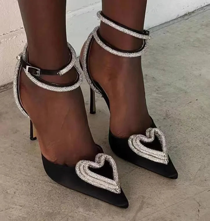 Women's black satin sandal with heart rhinestone, pointed toe, and cross ankle strap.