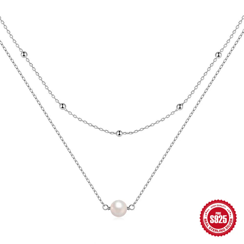 Close-up of a women's double layer sterling silver necklace with two round freshwater pearls on a geometric pendant.