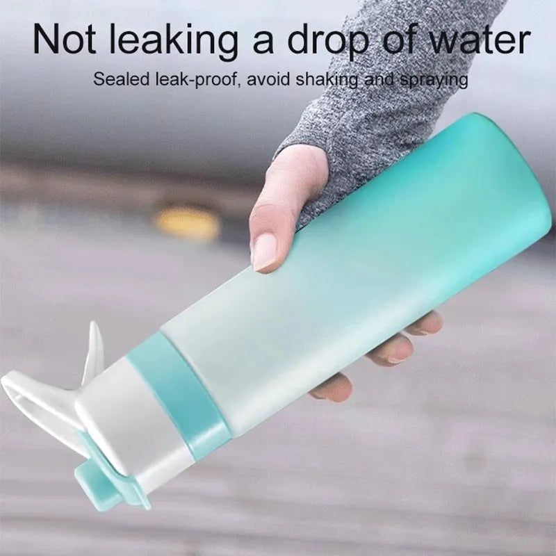White 700ml plastic spray water bottle with a black handle strap and leakproof lid on a table.