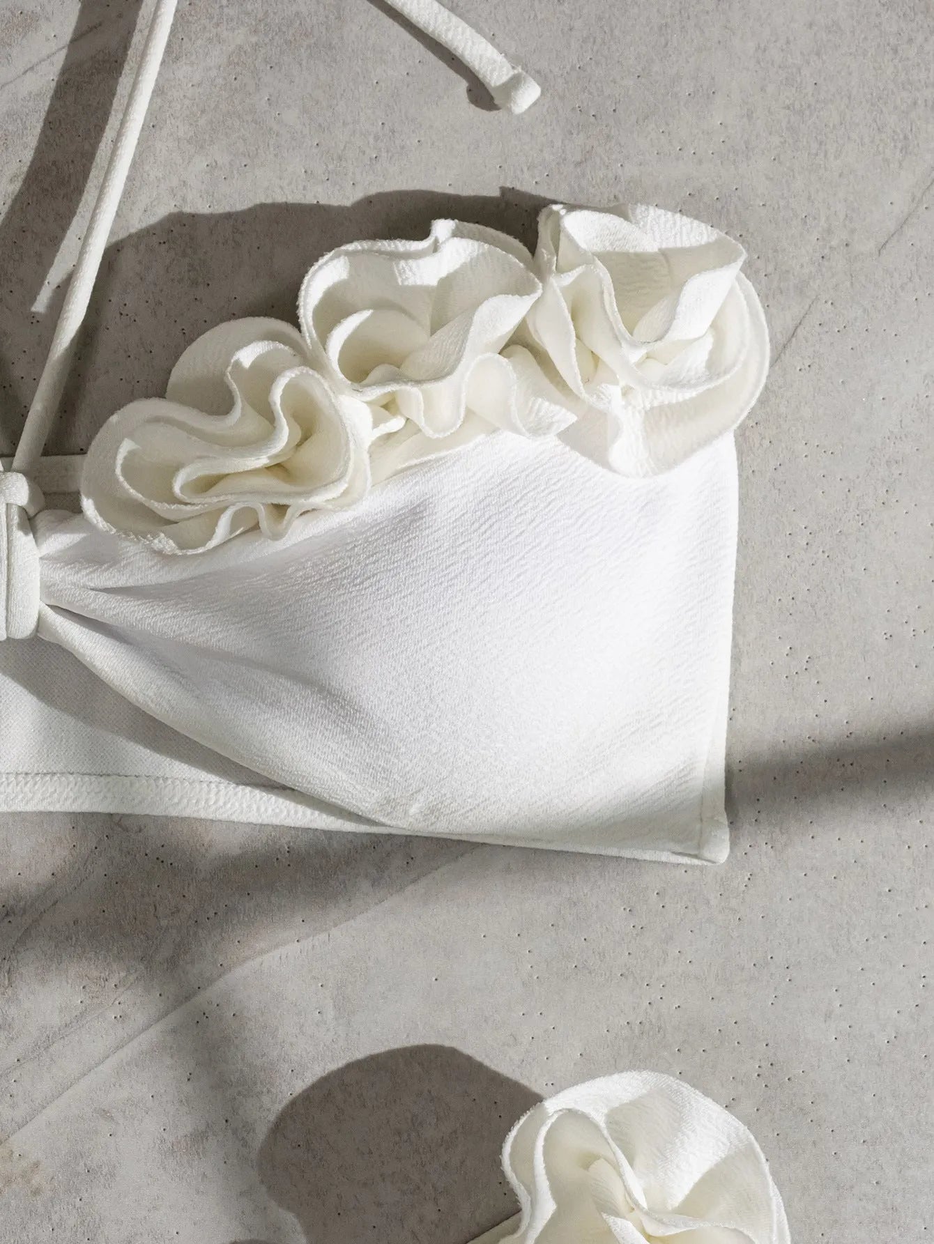 White halter neck lace-up bikini with three-dimensional floral embroidery and brief bottoms.