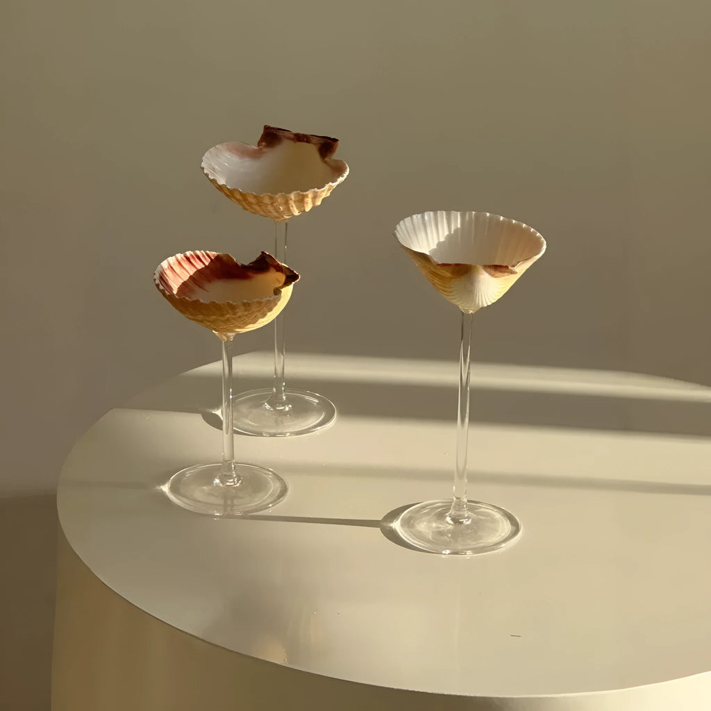 Handmade glass water cup with creative conch shell design, clear glass finish, side view
