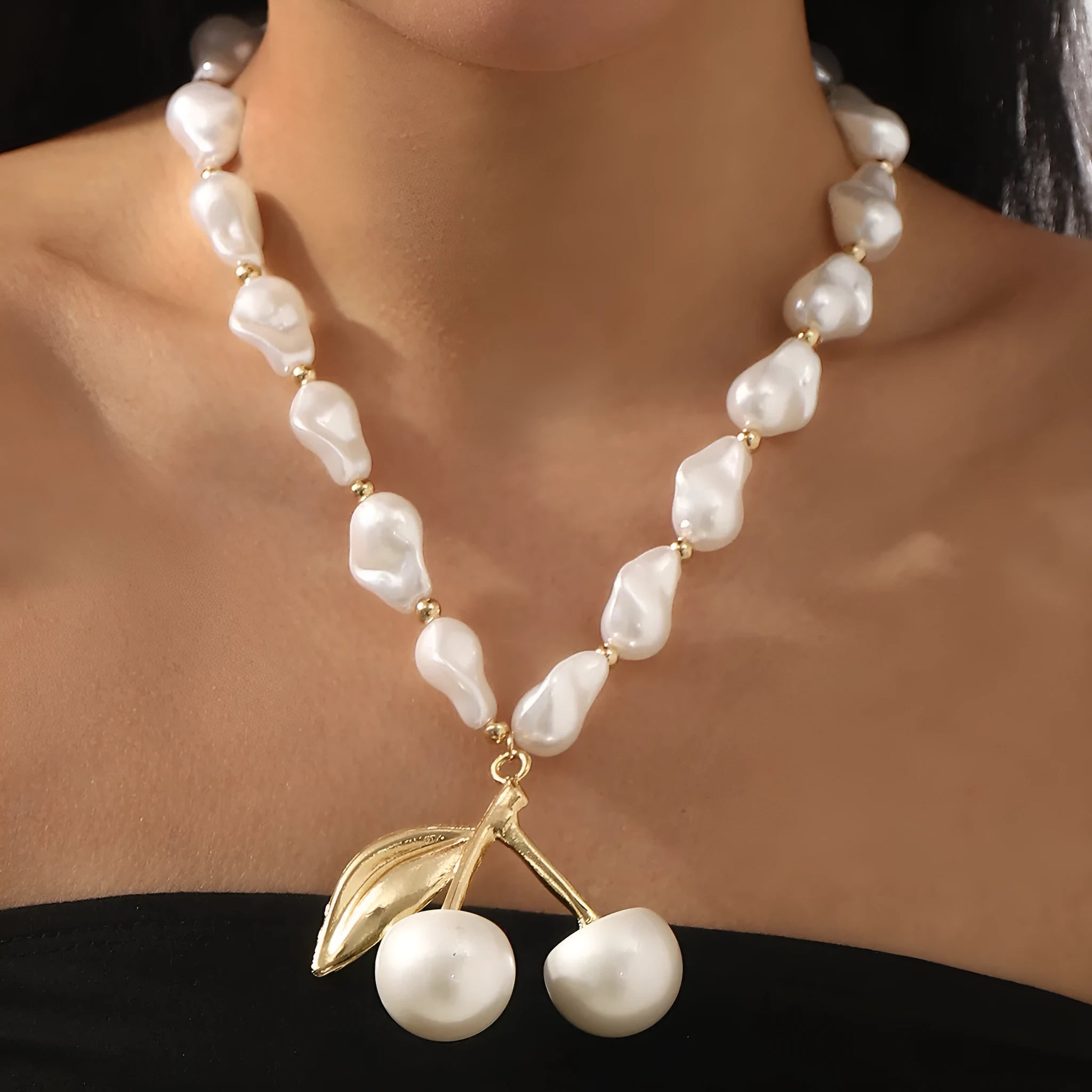 Gold electroplated cherry fruit pendant on an adjustable white pearl chain necklace for women.