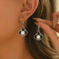 A pair of retro-style silver-coloured alloy earrings for women on a plain background.