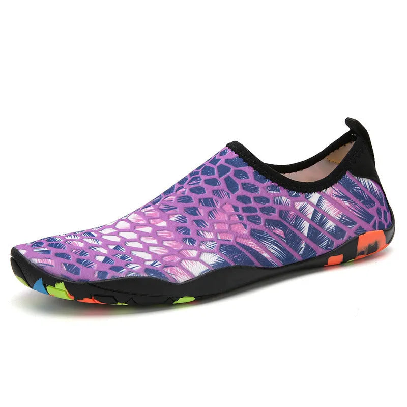 Blue and black Lycra fabric beach wading shoes with EVA foam soles on a sandy background.