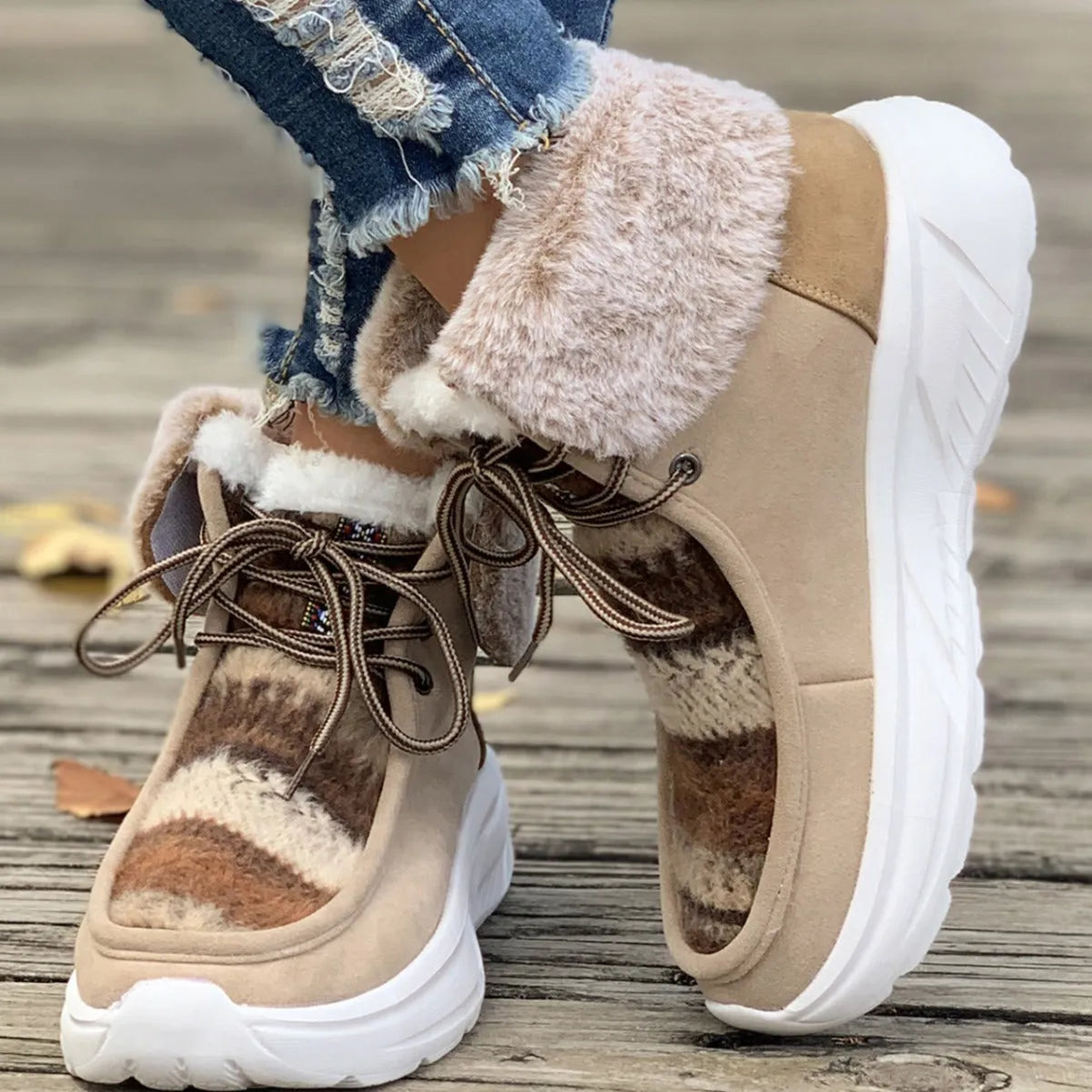 Beige women's lace-up suede mid-top snow boots with a thick sole on a winter background.