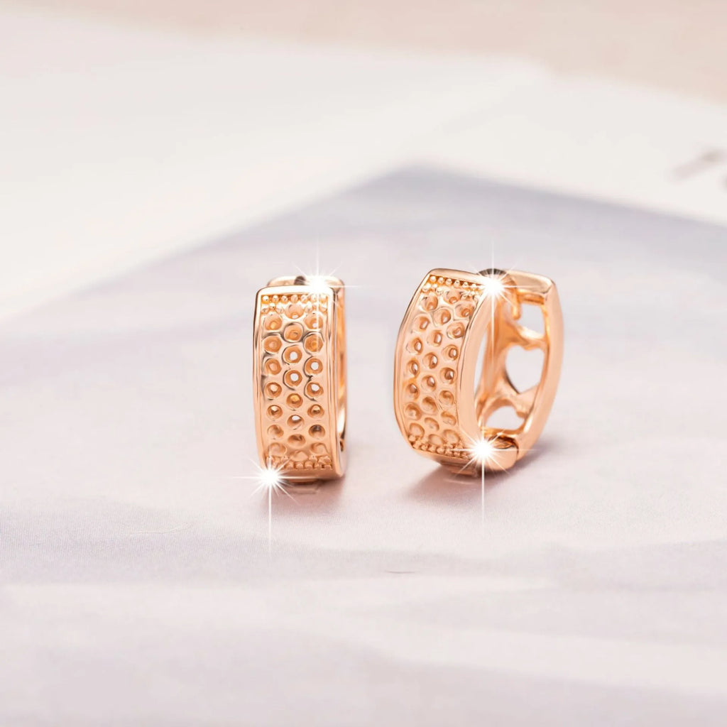 Rose gold hollowed out earrings with a three-heart design inside a circular shape.