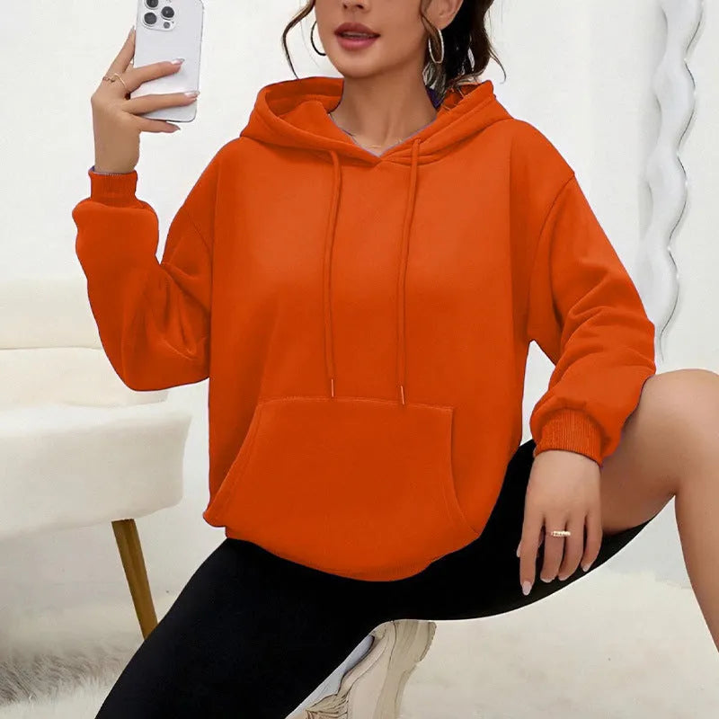 Women's loose grey sweatshirt with a front pocket and drawstring waist, worn with jeans.