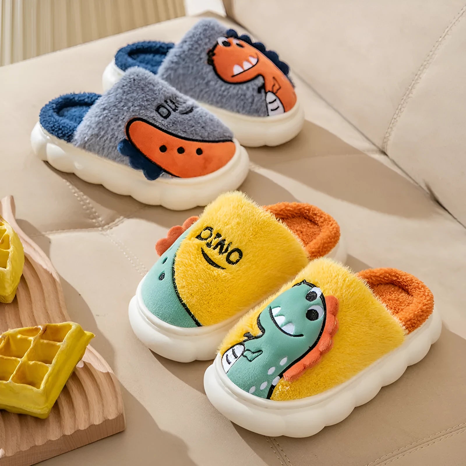 A pair of plush grey dinosaur-themed cotton slippers with a thickened sole for indoor wear.