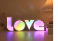 Colourful LED LOVE light decoration with rainbow lampshade on a table.