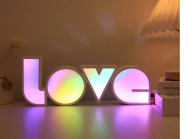 Colourful LED LOVE light decoration with rainbow lampshade on a table.