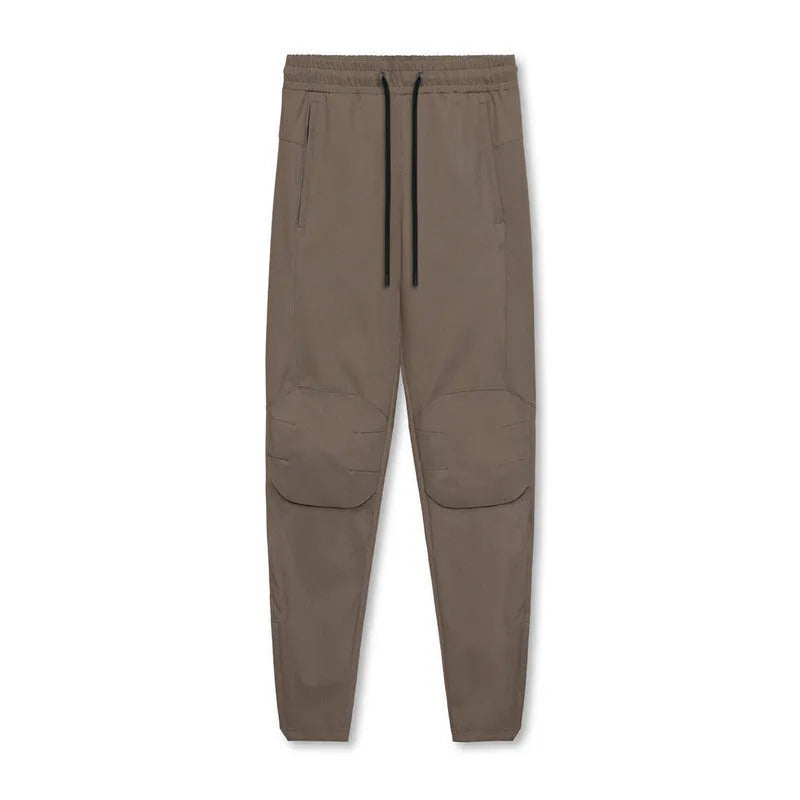 Men's loose grey running pants with ankle ties, laid flat to show mid-waist and full-length design.