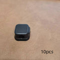White and black magnetic cable clips with adhesive backing holding a USB cable against a wooden desk edge.