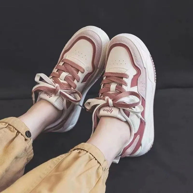 Pink and white low-top spring sneakers with rubber sole on a plain background