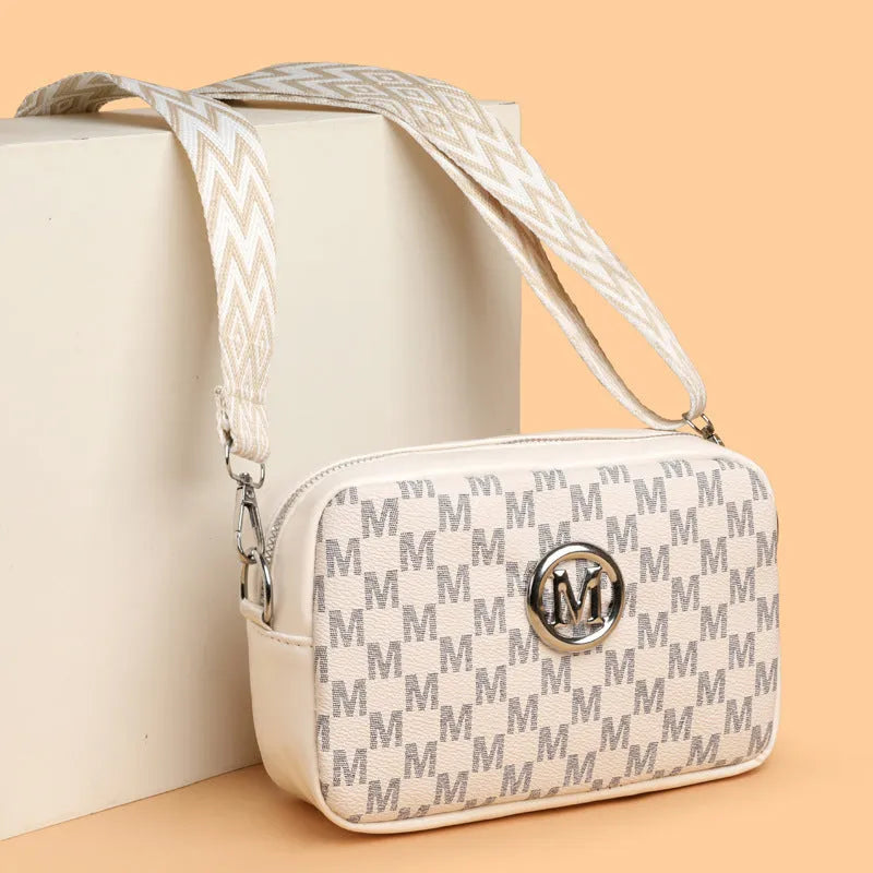 Black crossbody bag with wide strap and a three-dimensional front pocket.