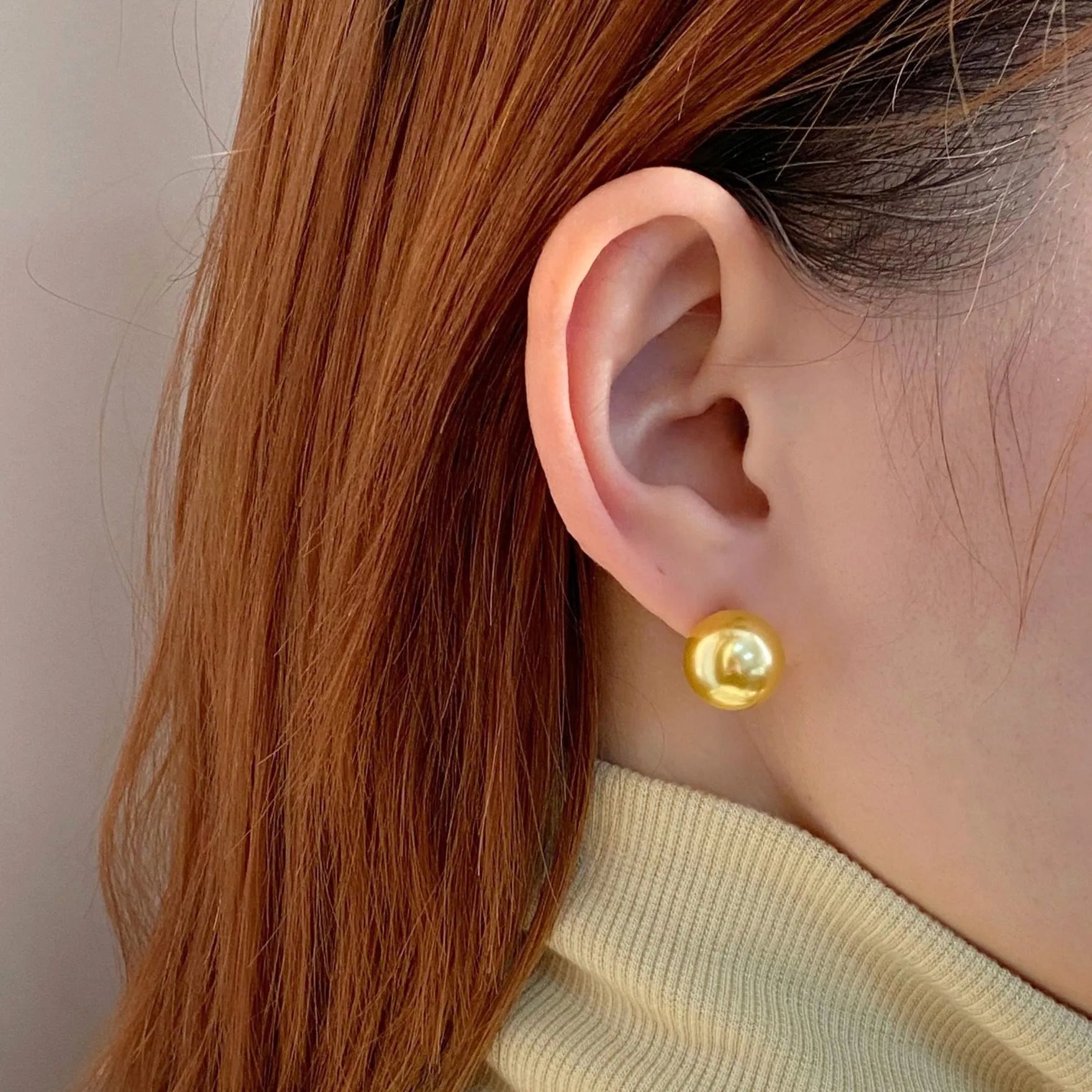 A pair of large geometric silver stud earrings with a central pearl and an eight-point star design detail.