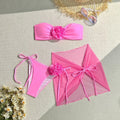 Women's pink bikini set with flower detail on tube top and a separate matching skirt.