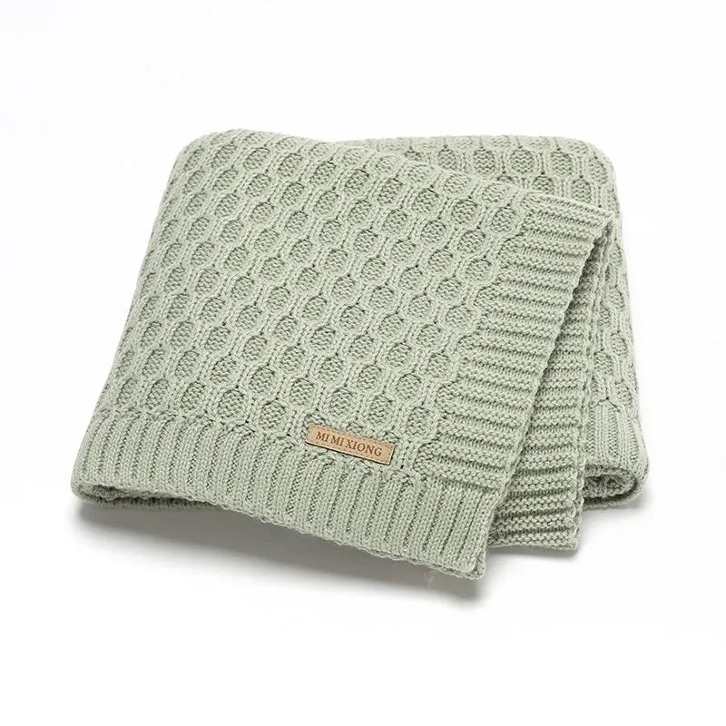 Solid colour acrylic infant blanket with textured lines, shown in a choice of five colours.