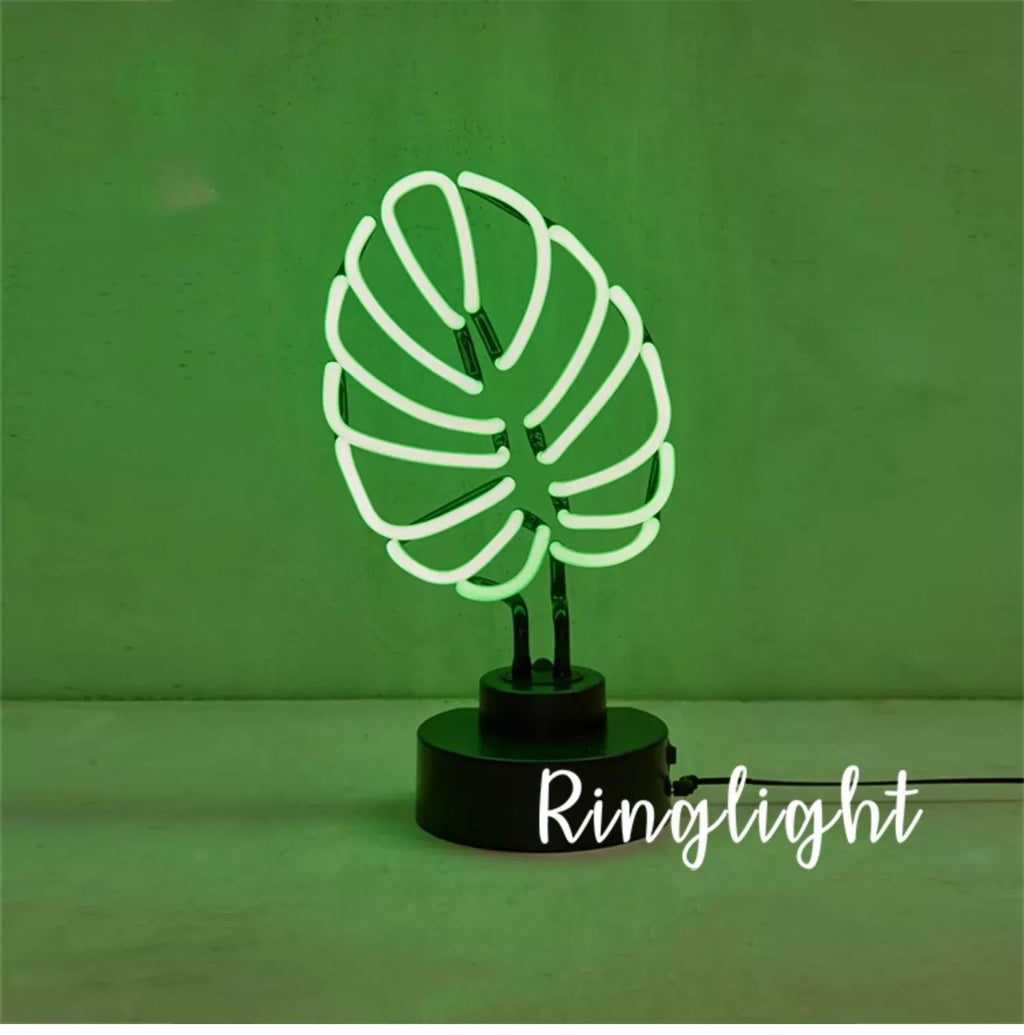Minimalist bamboo-shaped white desk lamp with green glowing tube on a wooden table.