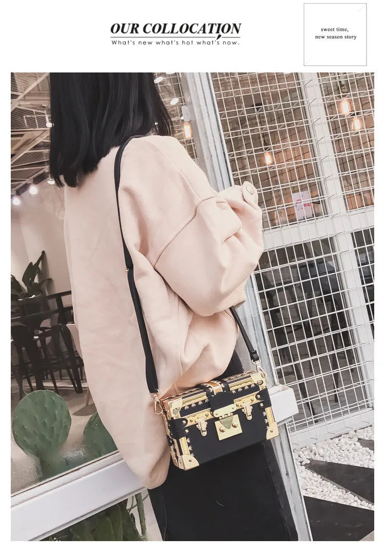 Women's hard black flap handbag with single strap, rivet details, and hasp closure.