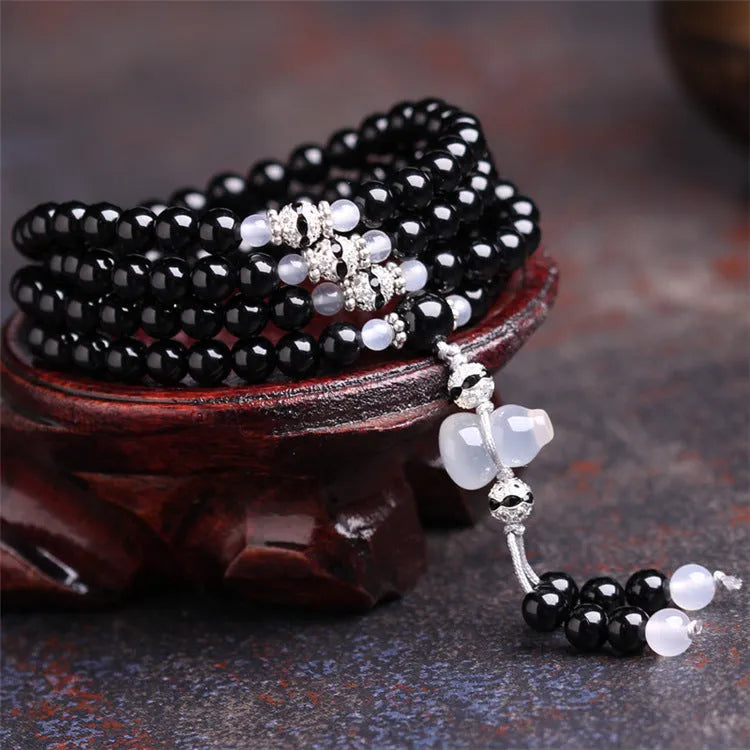 Natural black and red agate 108 bead bracelet with geometric shapes on a wrist.