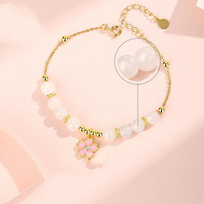 Close-up of a women's pink cherry blossom pendant and Hetian jade bead bracelet made from S925 silver.