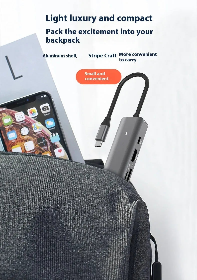 7-in-1 USB C card reader hub with multiple ports and SD card slots on a desk next to a laptop.