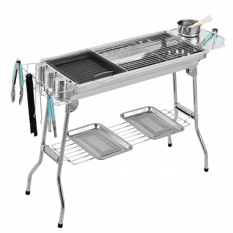 Stainless steel folding portable barbecue grill set up outdoors.