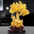 Citrine coloured resin small water turtle money tree Feng Shui ornament on a surface.